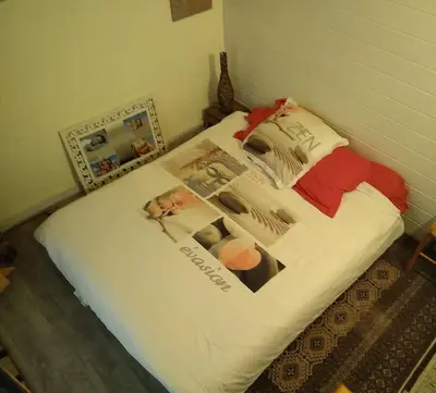 a bed with a white comforter with pictures on it at Gîte nature sous les châtaigniers in Zonza