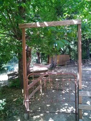 a cage in a park with a tree at Gîte nature sous les châtaigniers in Zonza