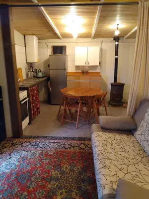 a kitchen with a wooden table and a kitchen with a couch at Gîte nature sous les châtaigniers in Zonza