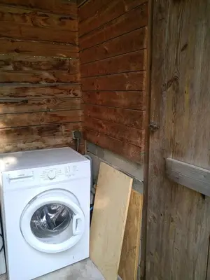 a washer and dryer in a room with a wooden wall at Gîte nature sous les châtaigniers in Zonza