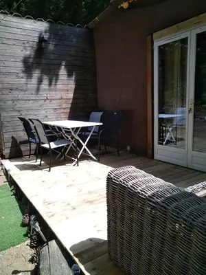 a table and chairs on a wooden deck with a building at Gîte nature sous les châtaigniers in Zonza