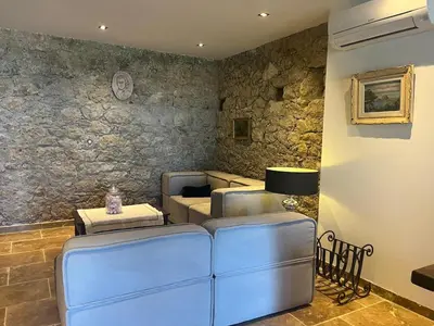 a living room with blue leather furniture and a stone wall at Casetta Teppe rosse in Aléria