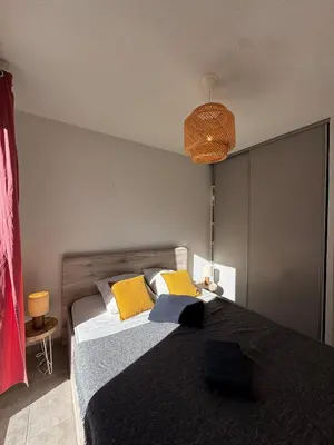 a bedroom with a large bed with yellow pillows at Mini-villa with swimming pool in Bonifacio residence in Bonifacio