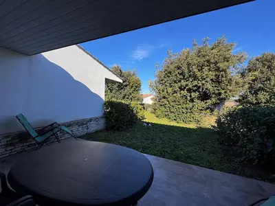 a patio with a table and a view of a yard at Mini-villa with swimming pool in Bonifacio residence in Bonifacio