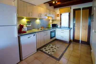 a kitchen with wooden cabinets and a white refrigerator at A nostra casetta corsa,Tania, en bord de mer in Ghisonaccia