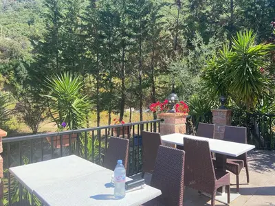 a table and chairs on a balcony with trees at Petit cocon près des Calanques de Piana in Porto Ota