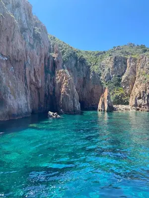 a boat in a body of water next to a cliff at Petit cocon près des Calanques de Piana in Porto Ota