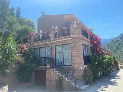 a brick building with a balcony and flowers on it at Petit cocon près des Calanques de Piana in Porto Ota