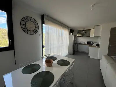 a kitchen with a table and a clock on the wall at Appartement sécurisé 100m du port de Porto Vecchio in Porto-Vecchio
