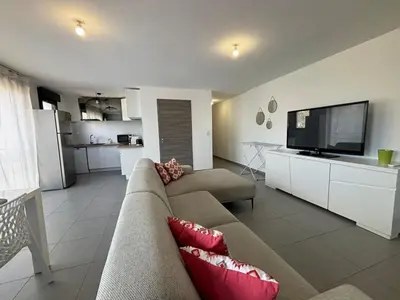 a living room with a couch and a flat screen tv at Appartement sécurisé 100m du port de Porto Vecchio in Porto-Vecchio
