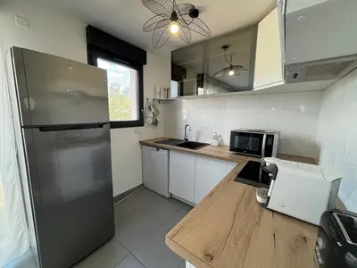 a kitchen with a stainless steel refrigerator and a window at Appartement sécurisé 100m du port de Porto Vecchio in Porto-Vecchio