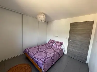 a bedroom with a purple bed and a door at Appartement sécurisé 100m du port de Porto Vecchio in Porto-Vecchio