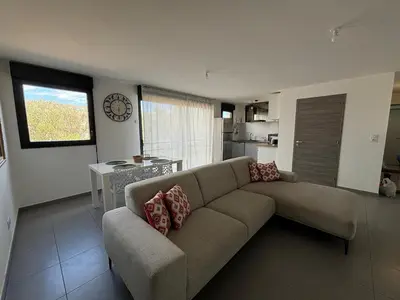 a living room with a couch and a kitchen at Appartement sécurisé 100m du port de Porto Vecchio in Porto-Vecchio