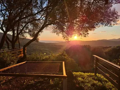 a bench on a hill with the sunset in the background at A Casa Faggia in Sollacaro