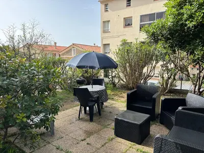 a patio with a table and chairs and an umbrella at Appartement plein centre avec jardin de 40m2 près des plages in Propriano