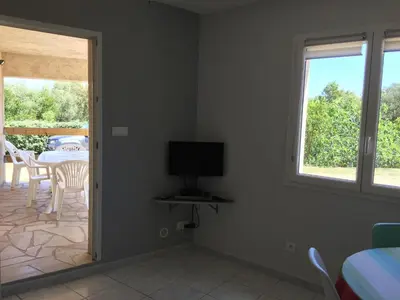 a white bedroom with a bed and two windows at Rez de jardin d'une villa in Zonza