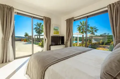 a bedroom with a large bed and large windows at Villa Suartello Porto Vecchio avec piscine privée in Porto-Vecchio
