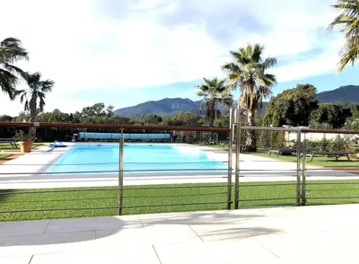 a swimming pool behind a fence with palm trees at Villa Suartello Porto Vecchio avec piscine privée in Porto-Vecchio