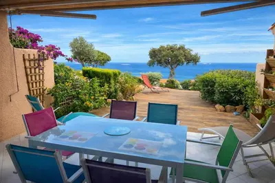 a table and chairs on a patio with a view of the ocean at Mini Villa Kallisté - vue mer exceptionnelle sur la baie de Palombaggia in Porto-Vecchio