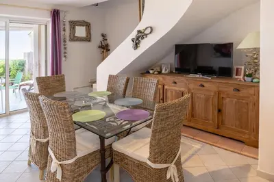 a dining room with a table and chairs and a television at Mini Villa Kallisté - vue mer exceptionnelle sur la baie de Palombaggia in Porto-Vecchio