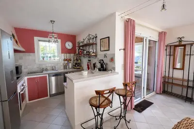 a kitchen with a counter and two stools at Mini Villa Kallisté - vue mer exceptionnelle sur la baie de Palombaggia in Porto-Vecchio