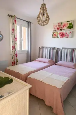 two beds in a room with a chandelier at Mini Villa Kallisté - vue mer exceptionnelle sur la baie de Palombaggia in Porto-Vecchio