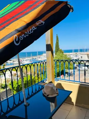 a umbrella sitting on a table on a balcony at Charmant T2 sur le Port de Plaisance de Solenzara in Sari Solenzara