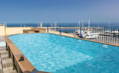 a large swimming pool with the ocean in the background at Charmant T2 sur le Port de Plaisance de Solenzara in Sari Solenzara