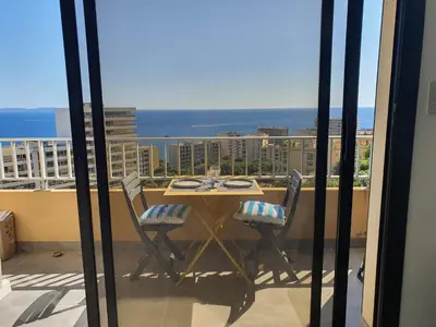 a table and chairs on a balcony with a view of the ocean at Le Balcon des Sanguinaires - studio cosy avec vue sur le Golfe d'Ajaccio et les Îles Sanguinaires in Ajaccio