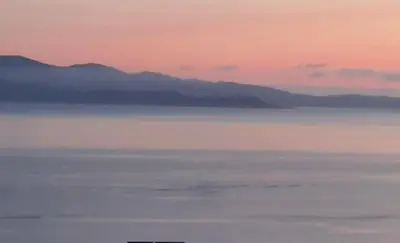 a view of the ocean with mountains in the background at Le Balcon des Sanguinaires - studio cosy avec vue sur le Golfe d'Ajaccio et les Îles Sanguinaires in Ajaccio