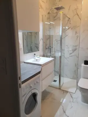 a bathroom with a washing machine and a shower at Le Balcon des Sanguinaires - studio cosy avec vue sur le Golfe d'Ajaccio et les Îles Sanguinaires in Ajaccio