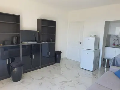 a kitchen with black cabinets and a white refrigerator at Le Balcon des Sanguinaires - studio cosy avec vue sur le Golfe d'Ajaccio et les Îles Sanguinaires in Ajaccio
