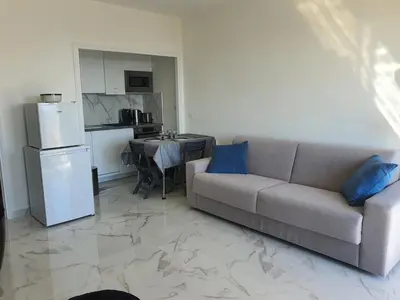 a living room with a couch and a kitchen at Le Balcon des Sanguinaires - studio cosy avec vue sur le Golfe d'Ajaccio et les Îles Sanguinaires in Ajaccio