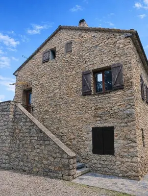 a stone building with windows on the side of it at Appartement charmant - Entre campagne et ville in Corte