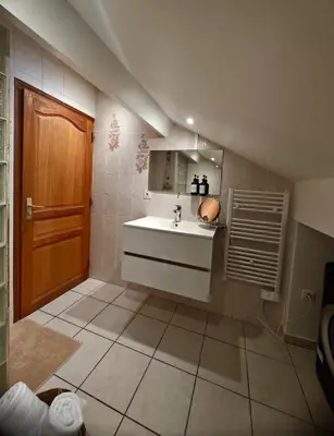 a bathroom with a sink and a wooden door at Appartement charmant - Entre campagne et ville in Corte