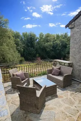 a patio with wicker chairs and a coffee table at Appartement charmant - Entre campagne et ville in Corte