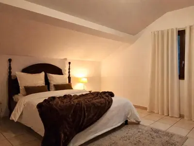 a bedroom with a large bed with a blanket on it at Appartement charmant - Entre campagne et ville in Corte