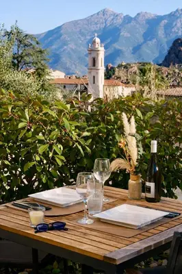 a wooden table with two glasses and a bottle of wine at Résidence A Stella in Piana