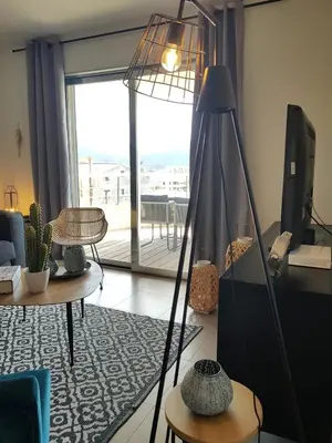 a living room with a floor lamp and a large window at Beautiful modern 4-star apartment with swimming pool and Wi-Fi in Porto-Vecchio