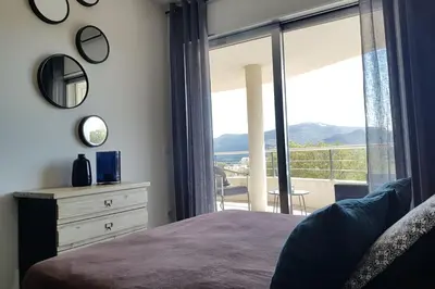 a bedroom with a bed and a view of a balcony at Beautiful modern 4-star apartment with swimming pool and Wi-Fi in Porto-Vecchio