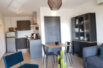 a living room with a table and a kitchen at Beautiful modern 4-star apartment with swimming pool and Wi-Fi in Porto-Vecchio