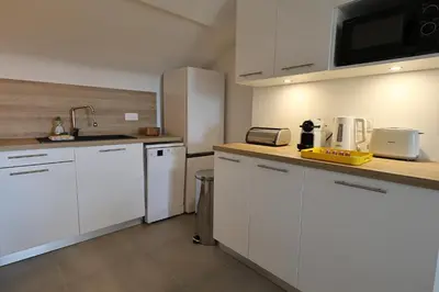 a kitchen with white cabinets and a white refrigerator at L'Orizonte - T3 vue mer piscine et plage in Pianottoli-Caldarello