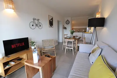 a living room with a couch and a tv and a table at L'Orizonte - T3 vue mer piscine et plage in Pianottoli-Caldarello