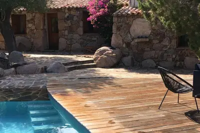 a chair sitting on a deck next to a swimming pool at Charming villa # Petra's House in Palombaggia in Porto-Vecchio