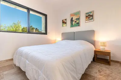 a bedroom with a white bed and two windows at Villa U Capu - Piscine Privée in Lecci