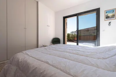 a bedroom with a bed and a large window at Villa U Capu - Piscine Privée in Lecci