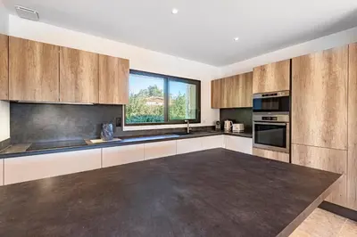 a kitchen with wooden cabinets and a large window at Villa U Capu - Piscine Privée in Lecci