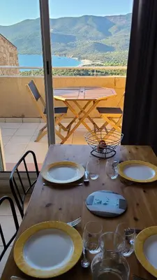 a wooden table with plates and wine glasses on it at Appartement 4 personnes - Soléa 137 - Vue Mer in Serra-di-Ferro