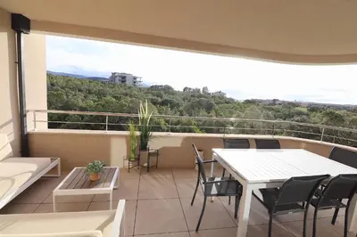 a balcony with a table and chairs and a large window at L'ÉCRIN - T2 65 m2 - Terrasse vue Mer & Maquis - Agosta plage à 200m- Parking privé in Albitreccia