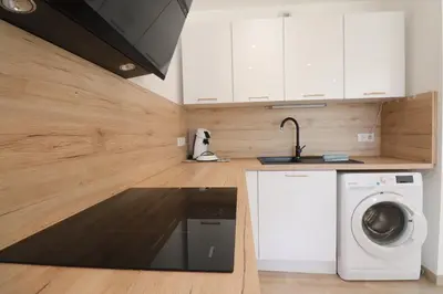 a kitchen with white cabinets and a washing machine at L'ÉCRIN - T2 65 m2 - Terrasse vue Mer & Maquis - Agosta plage à 200m- Parking privé in Albitreccia